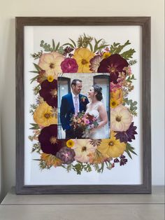 a wedding photo frame with flowers in the shape of a heart and a couple holding each other