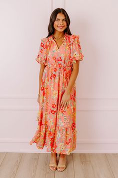 - Drape yourself in petals and twirl in the sun with this airy dress! - Chiffon material with a colorful abstract floral print - A built-in lining that ends above the ruffled hemline - A ruffled v-cut neckline with a tie detail - Short, loose ruffled sleeves - Pleated detail at the bodice - An elastic waistline - A flowy yet flattering silhouette that ends in a ruffled maxi length hemline Spring Peach Maxi Dress With Ruffles, Peach Ruffled Maxi Dress For Spring, Peach Ruffled Midi Dress For Garden Party, Coral Spring Vacation Dresses, Spring Vacation Coral Dresses, Spring Coral Vacation Dresses, Breezy Pink Ruffled Dress, Flowy Peach Maxi Dress With Ruffles, Pink Breezy Dress With Ruffles