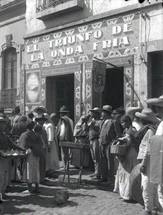 an old black and white photo of people standing in front of a building with writing on it