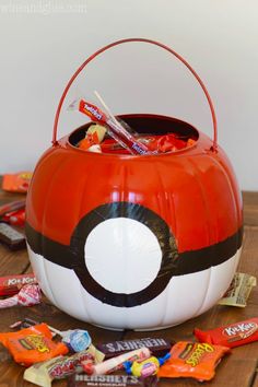 an orange and white pumpkin shaped bucket filled with candy sits on top of a wooden table