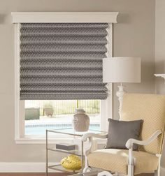 a living room with a chair, lamp and window covered in roman blind shades on the windowsill