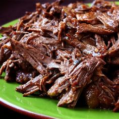 a green plate topped with shredded meat on top of a table