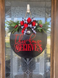 this house believe sign is hanging on the front door with red and black bow around it