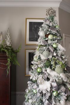 a white christmas tree decorated with green and silver ornaments