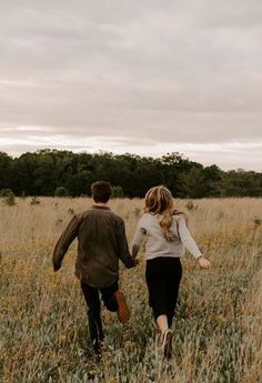 a man and woman walking through tall grass