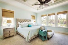 a bedroom with blue walls and white bedding, two nightstands, and a ceiling fan