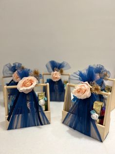 three small wooden boxes with blue organes and flowers in them on a white surface