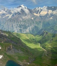 the mountains are covered in green grass and snow