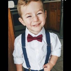 a young boy wearing a bow tie and suspenders