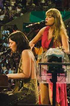 two women are playing instruments in front of a microphone and an audience at a concert