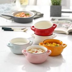 four bowls are stacked on top of each other in front of an open book and bowl