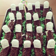 a tray filled with chocolate tombstones covered in green frosting and paper notes on them