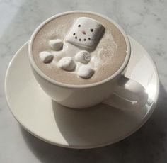 a cup of hot chocolate with marshmallows in the shape of a snowman