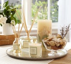 candles, flowers and other items are on a table in front of a window with windows