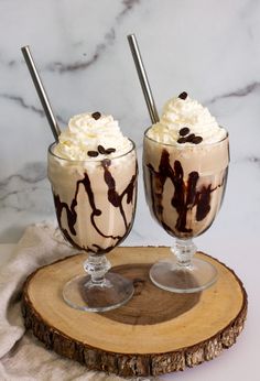 two glasses filled with ice cream on top of a wooden slice next to each other