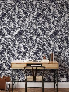 a desk and chair in front of a wallpapered room with waves on it