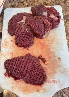 three pieces of meat sitting on top of a cutting board