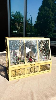 a yellow box sitting on top of a table next to a window with glass panes