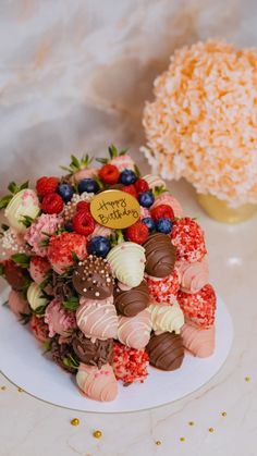 a cake with strawberries, raspberries and chocolates on it sitting on a plate