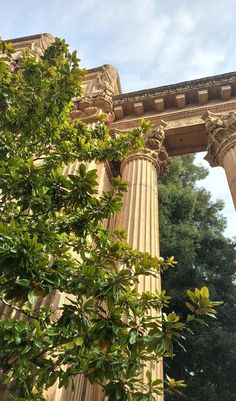 an old building with columns and trees in the foreground