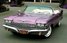 an old purple car is parked on the street