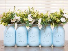 four blue mason jars with flowers in them