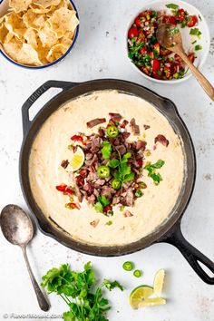 a skillet filled with hummus and tortilla chips next to a bowl of salsa