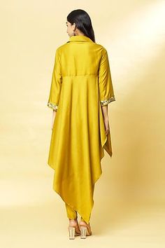 Mustard tunic with embroidery on the sleeve hems and spread collar. Comes with draped pants.
Component: 2
Pattern: Embroidery
Type Of Work: Sequin
Neckline: Spread Collar
Sleeve Type: Three Quarter
Fabric: Cotton Silk
Color: Yellow
Other Details: 
Asymmetrical hem
Pant with draped layer in front
Closure: Concealed button front
Occasion: Sangeet - Aza Fashions Elegant Yellow Kurta With Traditional Drape, Embellished Silk Tunic Kurta, Semi-stitched Yellow Kurta With Cutdana, Yellow Dhoti Kurta Women, Semi-stitched Yellow Sets With Cutdana Detail, Draped Pants, Drape Pants, Silk Tunic, How To Hem Pants