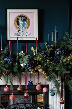 a fireplace decorated for christmas with ornaments and greenery hanging from it's mantle