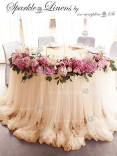 the table is covered with tulle and flowers