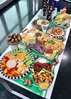 a table filled with different types of food and snacks on plates next to bottles of wine