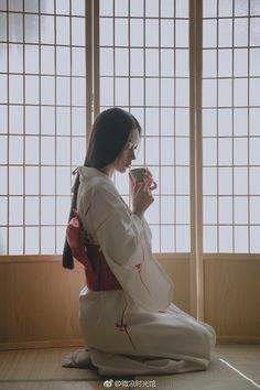 a woman sitting on the floor drinking from a cup