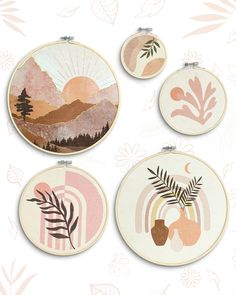 four embroidery hoops with different designs on them, including trees and mountains in the background