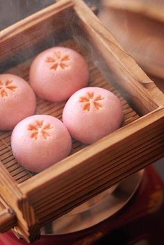 four pink donuts sitting in a wooden box