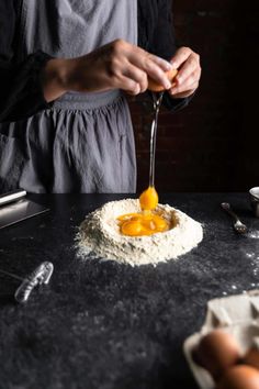 a person is grating eggs into flour on a black table with utensils