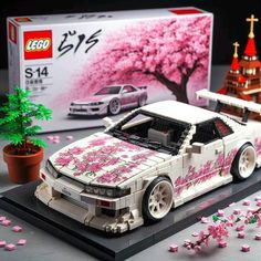 a lego model of a car with pink flowers in front of it and a box on the ground