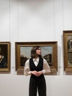 a woman standing in front of three paintings