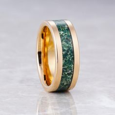 a wedding band with green and gold inlays on the inside, set against a white background