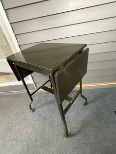 an old metal table sitting in front of a garage door on the side of a house