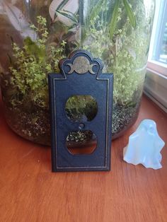 a glass jar with plants in it sitting on a table next to a metal holder