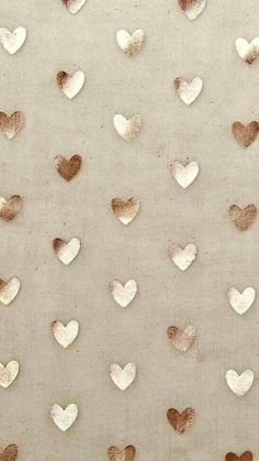 some gold hearts are on a white surface with brown spots and one is in the shape of a heart