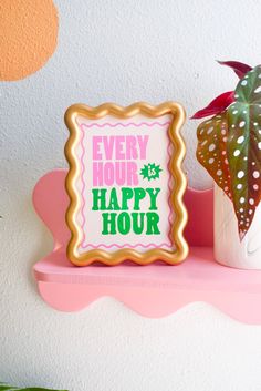 a sign that says every hour is happy hour next to a potted plant on a pink shelf