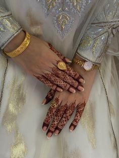 a woman's hands with hennap and gold bracelets on her wrist