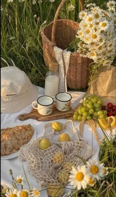 a picnic with food and flowers in the grass, including bread, milk, fruit, and other items