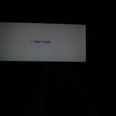 the first love message is projected on a screen in the dark, with someone holding their hand up