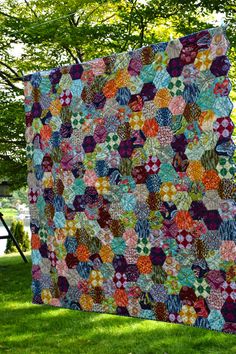 a large quilt is hanging on the grass