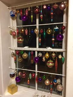 christmas ornaments are hanging on the window sill