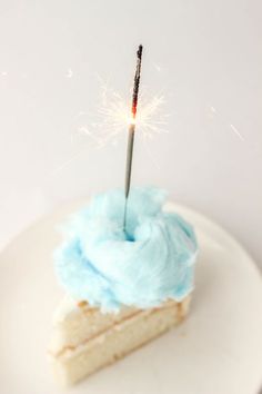 a piece of cake with blue frosting and a sparkler on top