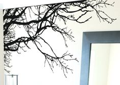 a bathroom with a sink and mirror next to a tree branch wall decal on the wall