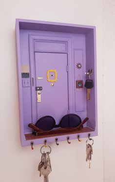 a purple door with keys hanging from it's sides and some key hooks on the wall